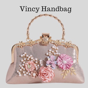 Könnte beinhalten: Eine blushfarbene Handtasche mit einem dekorativen Blumendesign. Die Tasche hat einen goldfarbenen Griff und Verschluss, mit Verzierungen aus rosa, blauen und weißen Blumen und Kunstperlen. Der Text "Vincy Handbag" steht oben.