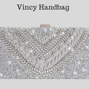 Puede incluir: Un bolso rectangular plateado con intrincados abalorios y cierre de broche. La bolsa está cubierta de adornos brillantes, con un diseño central. El texto "Vincy Handbag" está en la parte superior.