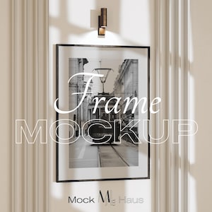 Puede incluir: Marco negro con una imagen en blanco y negro de una escena callejera con un tranvía. Las palabras "Frame Mockup" están superpuestas a la imagen. El marco cuelga de una pared blanca con molduras verticales.