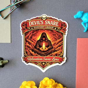 May include: A sticker with the text "DEVIL'S SNARE SUPPORT GROUP" and "Relaxation Saves Lives". The sticker features a hooded figure holding a candle, surrounded by fiery imagery. The design is framed with ornate red and gold details.
