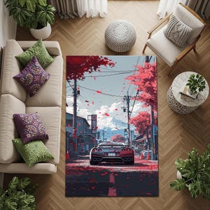 May include: A rectangular area rug featuring a stylized illustration of a red sports car driving down a street lined with red-leafed trees. The background includes Japanese buildings and a snow-capped mountain.