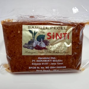 Pode incluir: Uma embalagem retangular de Sambel Pecel, um molho tradicional indonésio, com um rótulo dourado com o nome da marca "SINTI" e um gráfico de vegetais. A embalagem contém 100 gramas de produto.