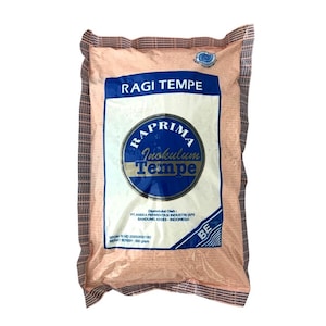 以下が含まれることがあります： 「RAGI TEMPE」とラベルされたパッケージ製品。ブランド名「RAPRIMA Inokulum Tempe」の青と白のラベルが付いています。パッケージは明るいピーチ色です。正味重量は500グラムです。