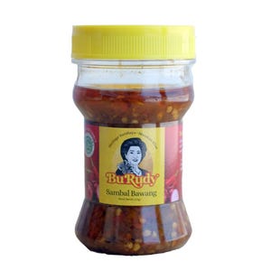 May include: A clear plastic jar filled with red chili paste, topped with a bright yellow screw-on lid. The label features a portrait of a woman, the text Bu Rudy, Sambal Bawang, and the weight specification of 110gr printed on the front.