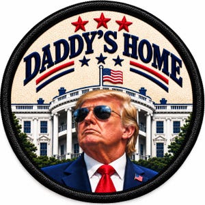 May include: A circular embroidered patch featuring a portrait of Donald Trump wearing sunglasses, a blue suit, and a red tie. The background shows the White House with an American flag. The text DADDY'S HOME is arched above in blue.
