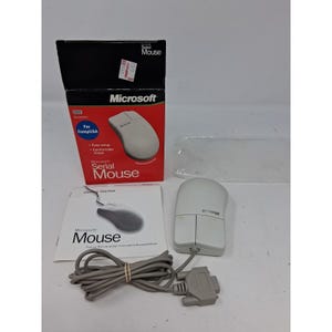 May include: A light gray Microsoft serial mouse with a long cord and a DB9 connector, accompanied by its original black and red cardboard packaging box and a printed getting started manual. The mouse features two primary buttons and a logo.
