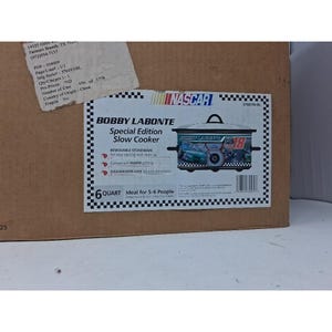 May include: A brown cardboard box featuring a product label for a Bobby Labonte Special Edition 6-quart slow cooker. The label displays the NASCAR logo, the number 18, and a graphic of a race car. It lists features like removable stoneware.