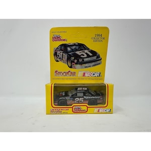 May include: Two die-cast NASCAR race cars in their original boxes. The boxes are yellow with black text and images of the cars. The cars are black with the numbers 51 and 25. The boxes read "1994 Collector Edition".