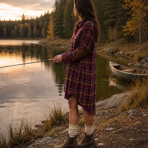 May include: A long-sleeved plaid shirt dress in shades of maroon, navy, and yellow, featuring a button-down front, a collar, and brown elbow patches. The garment is paired with cream-colored ribbed knit socks and brown leather ankle boots.