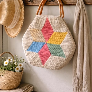 Peut inclure: Un sac fourre-tout en crochet beige avec un motif d'éclat d'étoile coloré en rose, jaune, bleu et vert. Le sac a des poignées en bois et est suspendu à un porte-manteau en bois avec un chapeau de paille et une écharpe.