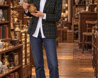 Puede incluir: Un blazer de cuadros en verde oscuro y azul marino sobre una camisa blanca de botones, combinado con vaqueros azul oscuro y mocasines de cuero marrón. El blazer presenta solapas de muesca, dos bolsillos delanteros y un cierre de un botón.