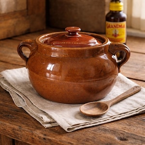 Puede incluir: Una taza de cerámica blanca con un asa negra y el texto "But first, coffee" en negro, con una fuente de estilo manuscrito. La taza está sobre una superficie blanca.