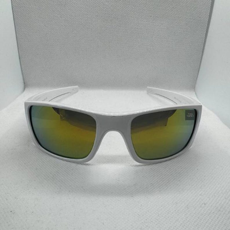 May include: White sunglasses with a rectangular frame and mirrored lenses that reflect a golden hue. The sunglasses have a sporty design and a subtle logo on the right lens.