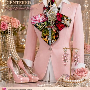 May include: A light pink blazer with a white collared shirt underneath, featuring a large, multi-colored floral and leopard print neck accessory with a pearl and crystal brooch. Matching light pink high-heeled pumps with crystal embellishments.