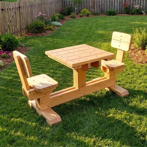 May include: A light brown wooden picnic table set featuring a square tabletop and two attached chairs with backrests. The furniture is constructed from smooth, light-colored wood planks and is positioned on a green lawn in an outdoor setting.