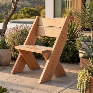 Puede incluir: Una silla de madera de tono claro con un diseño geométrico y patas gruesas e inclinadas que forman una X en los laterales. La silla tiene un asiento plano y un respaldo compuesto por dos listones de madera horizontales con veta natural.