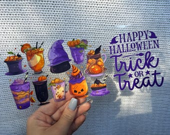 May include: A clear sticker featuring Halloween-themed illustrations of drinks and a witch's hat. The sticker includes the text "Happy Halloween Trick or Treat" in purple and white. The drinks are in various colors, including orange, purple, and black.