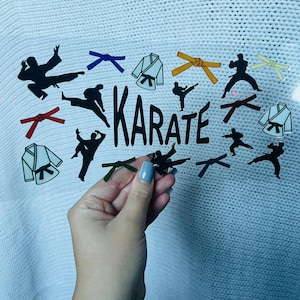 May include: A clear sticker sheet featuring karate-themed graphics. The design includes black silhouettes of karate practitioners in action, karate uniforms, and colored belts. The word "KARATE" is printed in black block letters.
