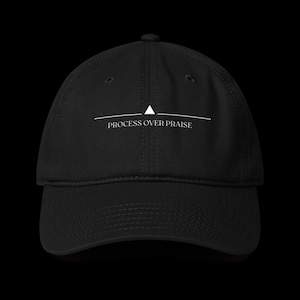 Könnte beinhalten: Schwarze Baseballkappe mit dem weißen Text "PROCESS OVER PRAISE". Die Kappe hat ein weißes Dreieck über dem Text. Der Hut ist aus strapazierfähigem Stoff gefertigt und hat einen gebogenen Schirm.
