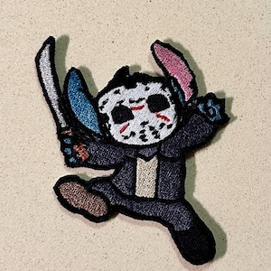 Pode incluir: Patch bordado com um personagem de desenho animado usando uma máscara de Jason Voorhees, segurando duas facas. O personagem está vestindo um terno azul escuro com uma camisa bege clara. O patch tem uma borda preta.