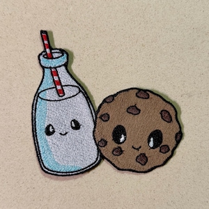 May include: Embroidered patch showing a cartoon milk bottle with a red and white striped straw and a chocolate chip cookie. Both have smiling faces and are outlined in black. The milk bottle is light blue and white.