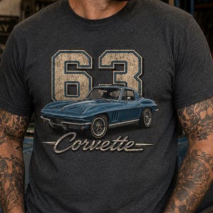 May include: A dark charcoal grey short-sleeve t-shirt featuring a graphic print of a blue 1963 Corvette car, the large number 63 in a distressed beige font, and the word Corvette in a classic script font centred on the chest area.