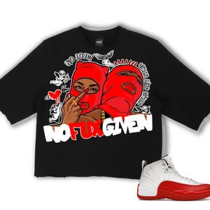 Puede incluir: Camiseta negra con dise&ntilde;o gr&aacute;fico que presenta dos figuras con pasamonta&ntilde;as rojos, el texto "NO FUX GIVEN" y un par de zapatillas blancas y rojas. La camiseta tiene un dobladillo sin rematar.