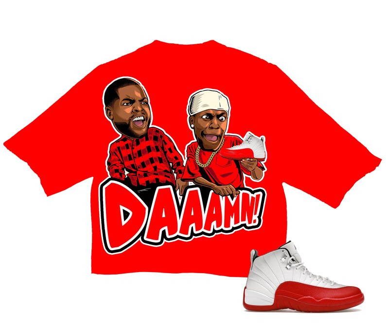 Puede incluir: Camiseta roja con un gr&aacute;fico de dibujos animados de dos hombres y la palabra "DAAAMN!". Una zapatilla Air Jordan 12 blanca y roja tambi&eacute;n est&aacute; en la imagen. La camiseta presenta un dise&ntilde;o audaz y un tema l&uacute;dico.