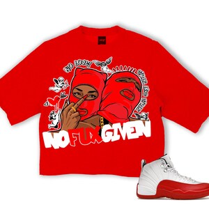 Puede incluir: Una camiseta roja con un gr&aacute;fico de dos figuras con pasamonta&ntilde;as rojos, con el texto "NO FUX GIVEN". Una zapatilla blanca y roja est&aacute; en la esquina inferior derecha. La camiseta tiene un corte amplio y cuadrado.