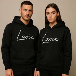 May include: Two black hoodies with the word "Lavix" in white script across the chest. The hoodies have a front pocket and a hood. The background is a solid, neutral color.
