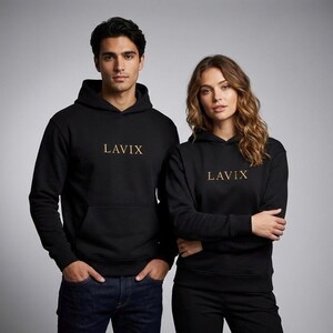 May include: Two people wearing black hoodies with the word "LAVIX" in gold lettering. The hoodies have a front pocket and a drawstring hood. The background is a solid gray.