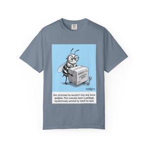 May include: A blue t-shirt featuring a cartoon bee wearing glasses and holding a box labeled "GADGET CO MYSTERIOUS ARRIVAL." Text below reads: "Ben promised he wouldn't buy any more gadgets. Five minutes later a package mysteriously arrived by itself he said."