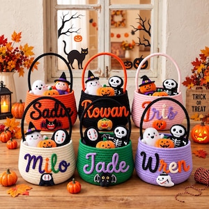May include: Six round woven rope baskets for Halloween, each featuring a sturdy handle and a personalised name in cursive script. The baskets are orange, black, pink, cream, green, and purple, decorated with plush ghosts, skeletons, and pumpkins.