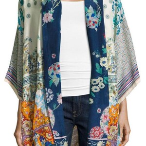 May include: A colorful kimono-style garment with a floral pattern. The open-front design features a navy blue panel with floral designs, complemented by cream and orange patterned sections. The sleeves have a patterned border.
