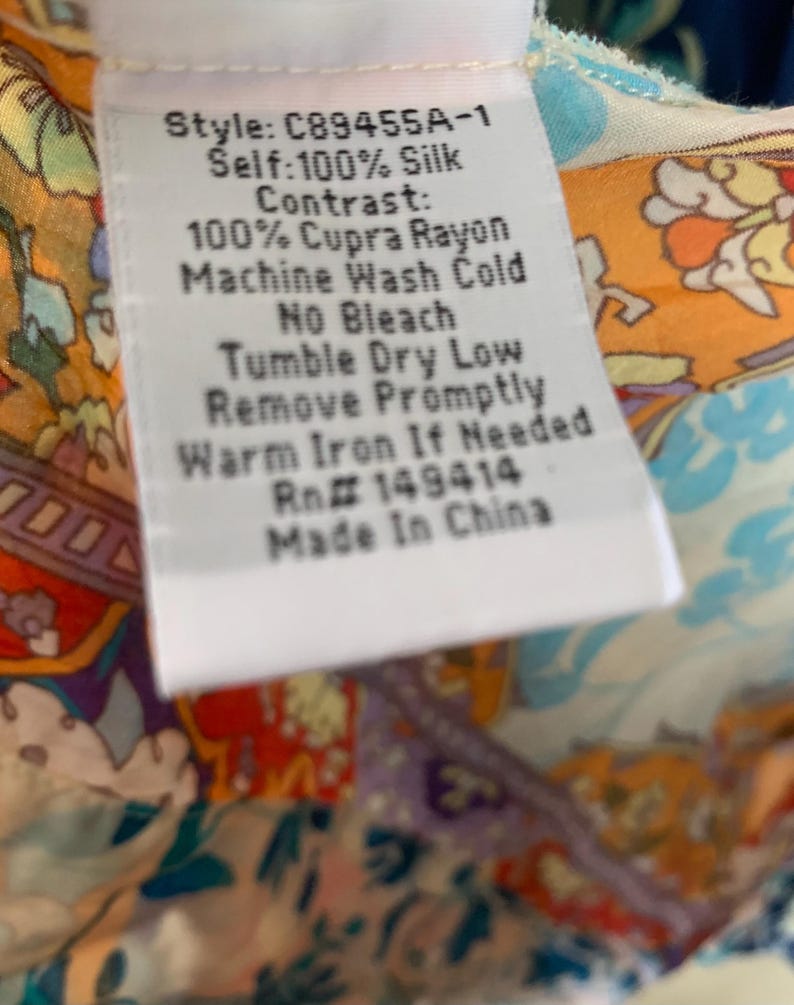 May include: A white clothing tag with black text, including the style number C89455A-1, fabric composition, and care instructions. The tag is set against a colorful patterned fabric background.