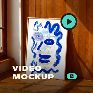 Puede incluir: Una impresión artística enmarcada que presenta un rostro con pinceladas azules sobre un fondo blanco. La obra de arte está apoyada contra una pared de madera. Las palabras "VIDEO MOCKUP" se muestran en la parte inferior izquierda del marco.