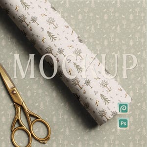 Puede incluir: Un rollo de papel de regalo con un patrón de bosque con árboles y pájaros, con la palabra "MOCKUP" en letras grandes. Un par de tijeras doradas está en la esquina inferior izquierda. El fondo tiene un patrón de bosque a juego.