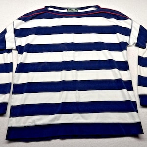 May include: A long-sleeve shirt featuring horizontal navy blue and white stripes. The garment has a round neckline with a thin red trim detail and a label at the inner collar that reads L-RL. The cuffs and hem are finished with solid navy blue bands.