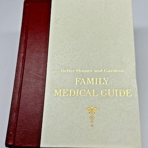 May include: A hardback book titled "Better Homes and Gardens Family Medical Guide." The book has a cream cover with gold lettering and a medical symbol. The spine is a deep red colour.