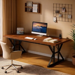 May include: A large, dark wood desk with black metal legs, a computer monitor, and a beige office chair. The desk has a keyboard, mouse, and an open book. A small calendar and a wall-mounted shelf are also visible.