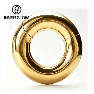 May include: A polished gold-tone circular hoop ring featuring a hinged segment closure. The surface is smooth and reflective, displaying a high-shine finish. The text "INNER GLOW" and a circular logo are positioned in the upper left corner of the image.