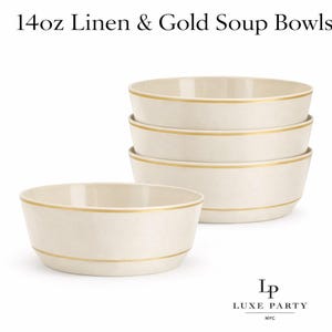 Puede incluir: Cuencos de sopa color crema con una banda dorada alrededor del borde y una banda dorada decorativa. Los cuencos están etiquetados como "14oz Linen & Gold Soup Bowls". La imagen muestra una pila de cuatro cuencos y un cuenco delante.