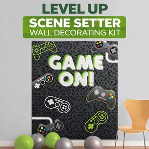 May include: A wall decorating kit featuring the text "GAME ON!" and controller graphics. The kit includes a large black backdrop with a pixelated design, green and grey balloons, and a wooden chair.