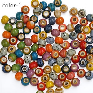 May include: A selection of colourful ceramic beads in shades of blue, green, orange, yellow, and purple. The beads are round with a hole through the centre, suitable for jewellery making or crafts. The text "color-1" is in the upper left corner.