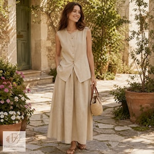 May include: A sleeveless beige linen vest with a button-down front and a matching floor-length linen skirt. The vest features a round neckline and a tailored fit, while the skirt has a full, flowing silhouette. A woven straw handbag is included.