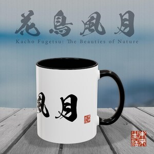 以下が含まれることがあります： 黒い内側とハンドルが付いた白いセラミックマグ。マグには日本の書道と「Kacho Fugetsu: The Beauties of Nature」というテキストが特徴です。赤いスタンプがマグの右側にあります。