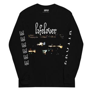 Puede incluir: Una camiseta negra de manga larga con el texto blanco lifelover sobre un gráfico borroso de paisaje urbano nocturno en el pecho. La manga izquierda muestra la palabra lifel repetida verticalmente en blanco, y la derecha tiene la palabra EROTIC.