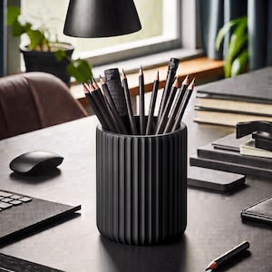 May include: A matte black cylindrical pencil holder with a vertical ribbed texture. The container is filled with several sharpened black pencils and one black mechanical pencil, all standing upright within the circular opening of the holder.
