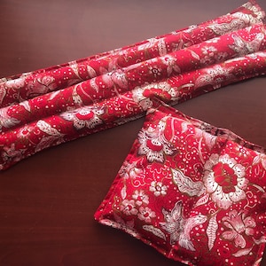 May include: Two red and white floral patterned heating pads. One is rectangular and long, and the other is square. The pads are made of fabric and are designed for therapeutic use.