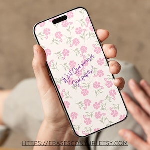 Puede incluir: Un teléfono inteligente que muestra un fondo de pantalla floral con flores rosas y tallos verdes sobre un fondo crema. La pantalla presenta el texto "What God promised, God fulfills" en escritura púrpura. El teléfono está en una mano.